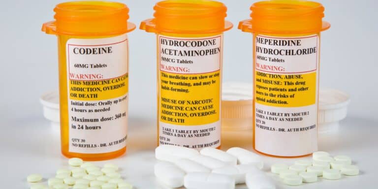 Prescription drug bottles labeled with warnings about addiction, overdose, and death, emphasizing the dangers of drug abuse, drug detox, and rehab. Focus on safe detox and recovery from substance addiction.