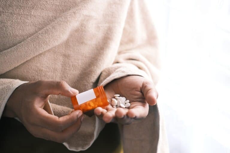 Prescription medication pills in a person's hand for drug detox and addiction recovery.