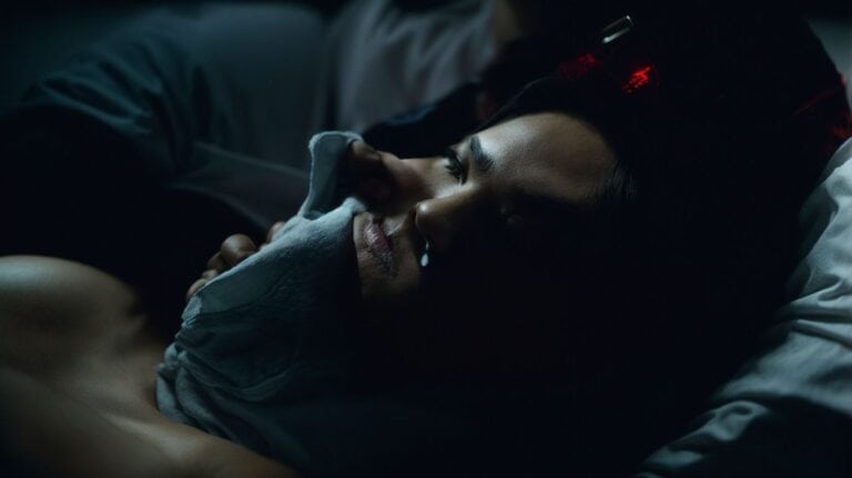 A woman lying in bed, experiencing discomfort during drug detox, holding a tissue to her face to soothe cravings or symptoms of withdrawal.