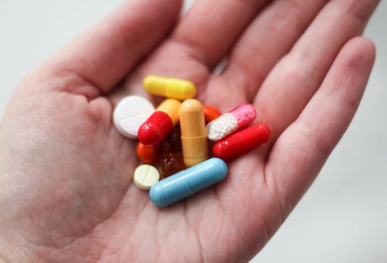 Pills and capsules in a person's hand, symbolizing drug detox and addiction treatment.