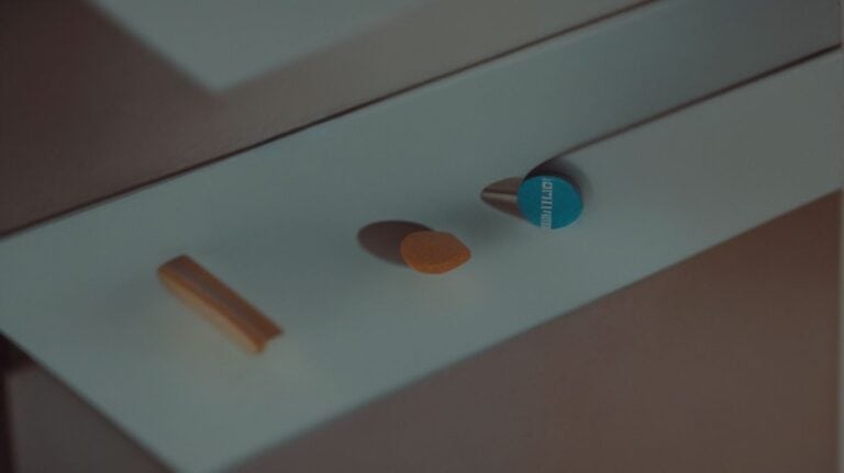 Blister pack of pills and an orange pill on a medical cabinet surface, representing drug detox and rehab treatment options for addiction recovery.